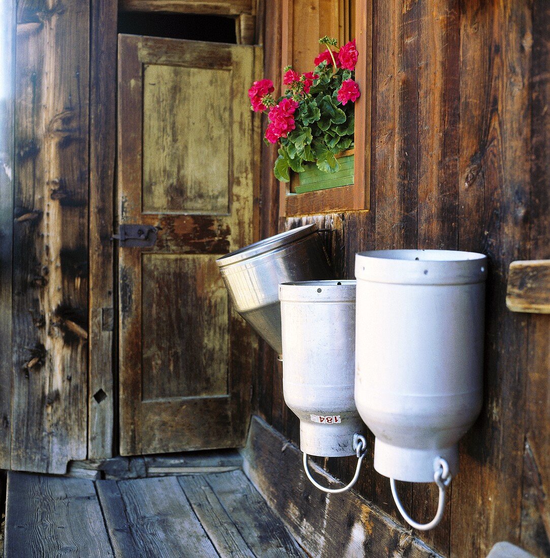 Three milk cans on the wall of a wooden house