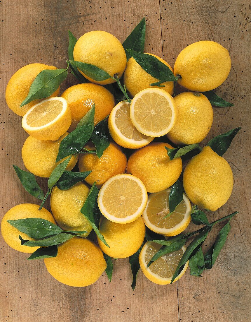 Lemons with leaves on wooden background