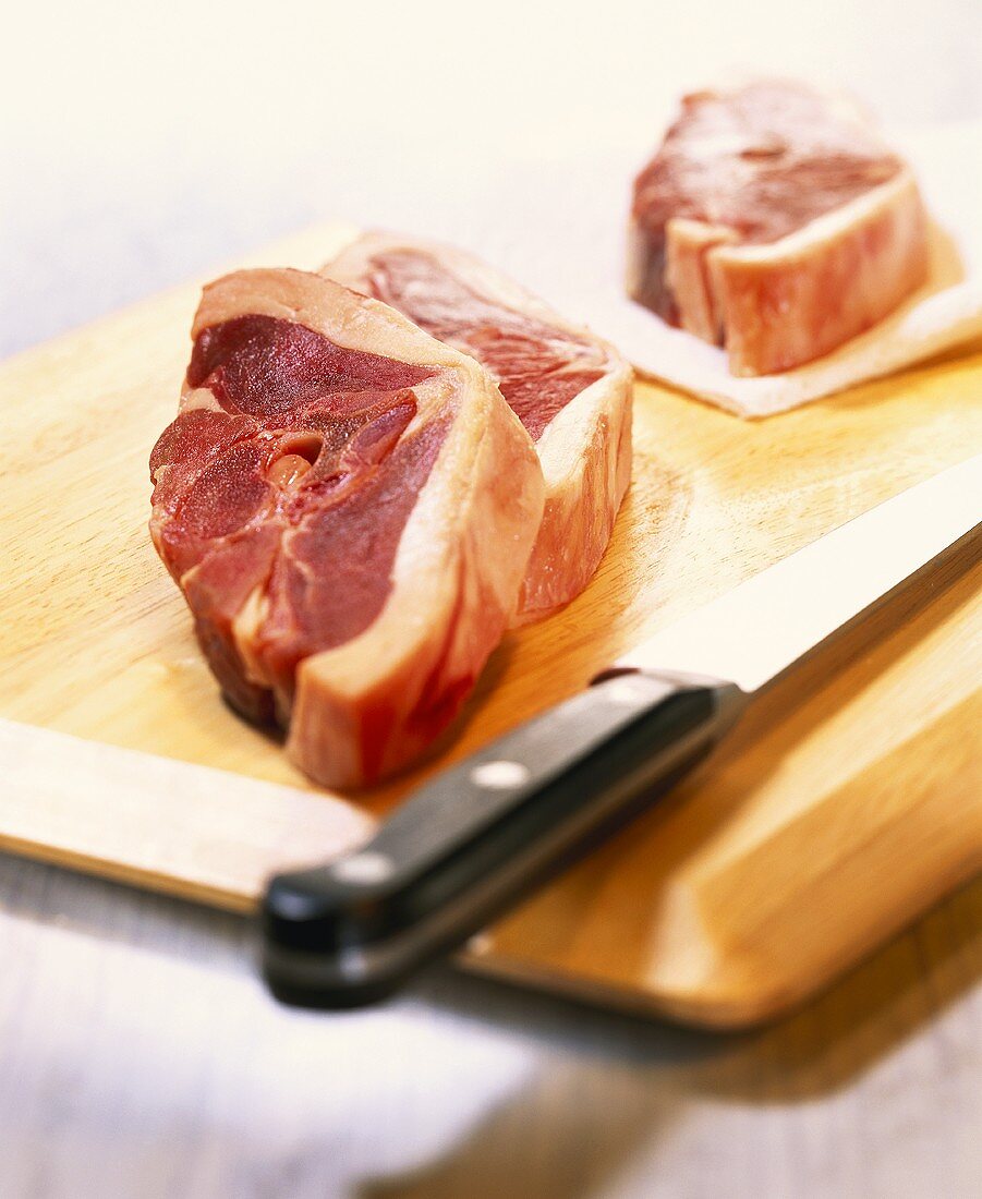 Lamb cutlets with knife on wooden board