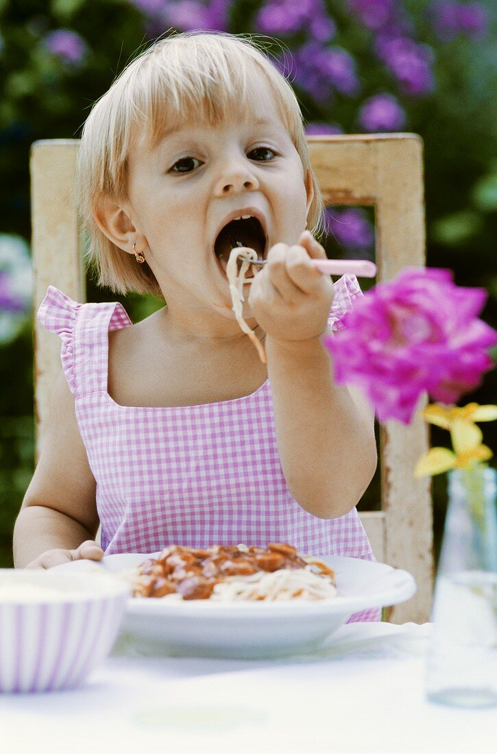 Kleines Mädchen isst Spaghetti im Freien