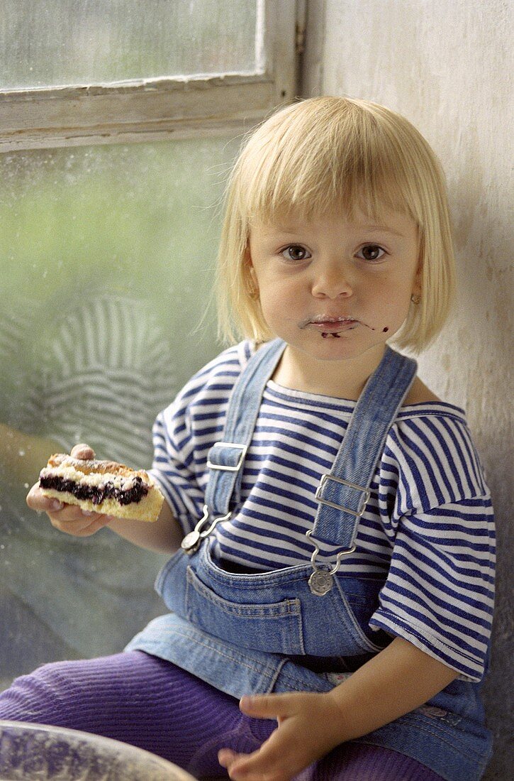Kleines Mädchen hält ein Stück Kuchen in der Hand
