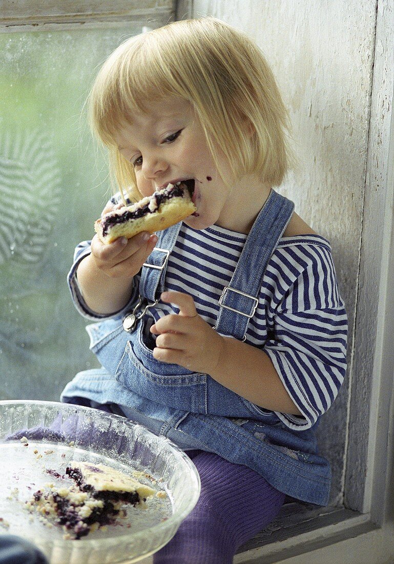 Kleines Mädchen isst ein Stück Kuchen