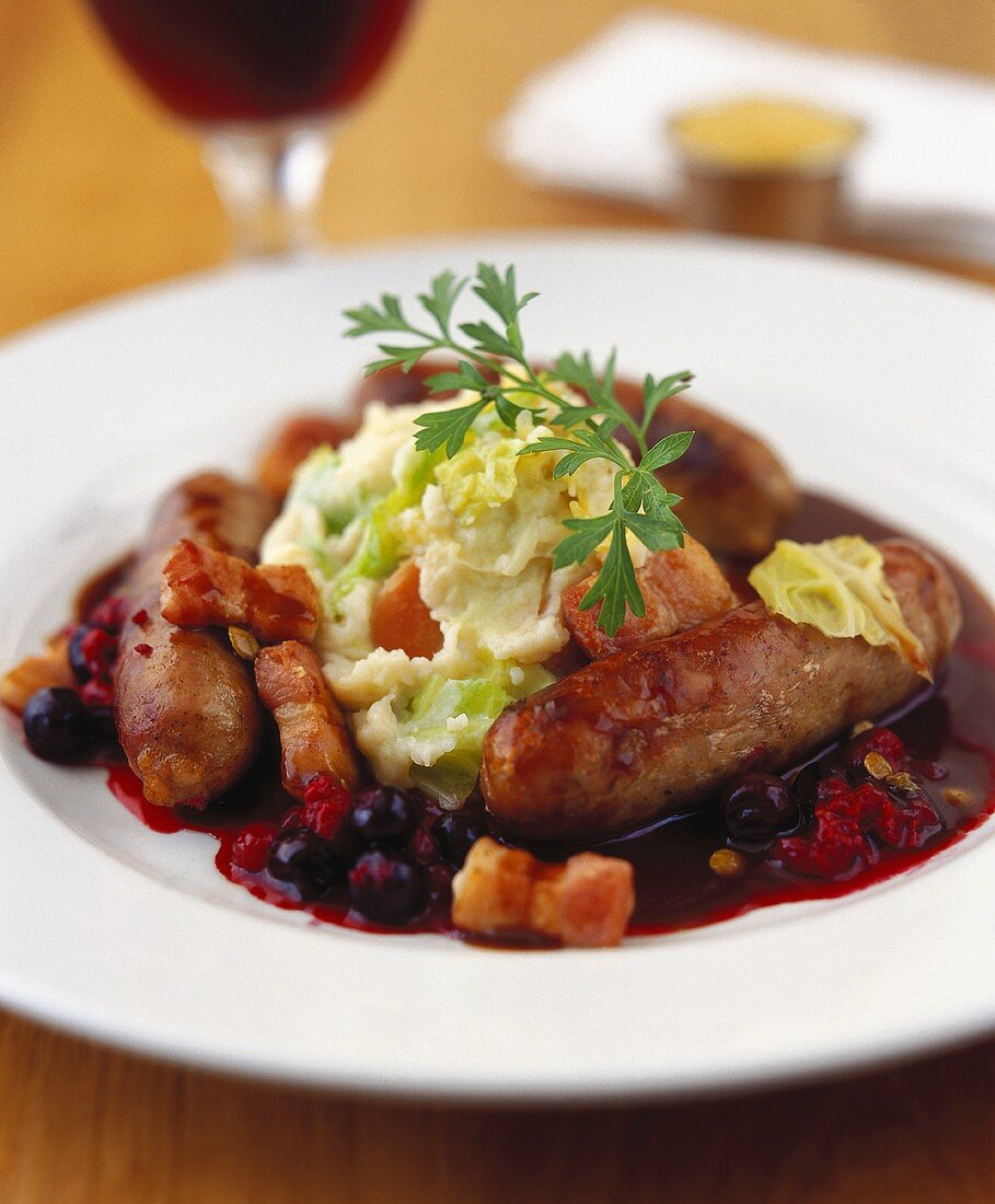 Sausages with mashed potato, bacon and blueberry sauce 