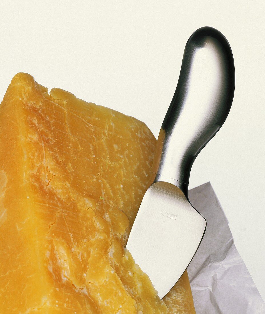 A piece of hard cheese with knife