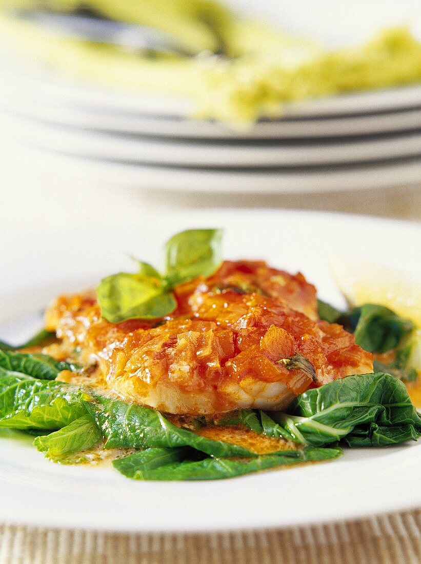 Fish fillet with tomato sauce on leafy vegetables