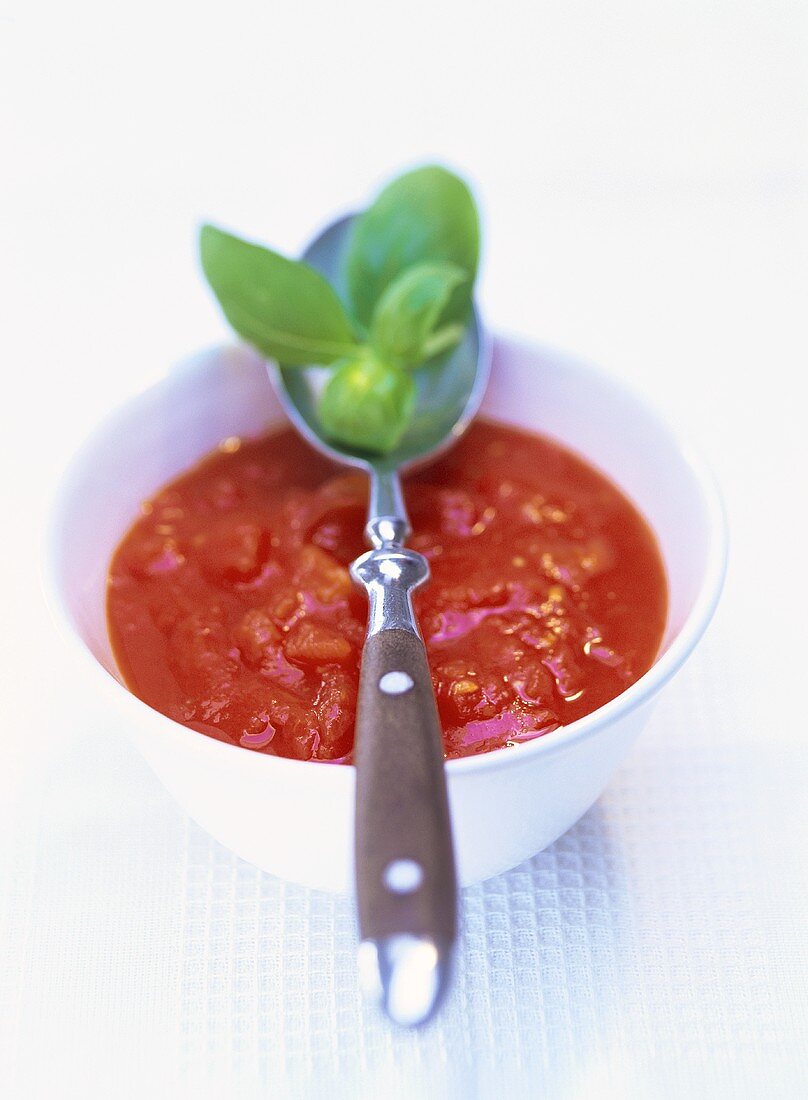 Tomato sauce in a bowl with basil leaves