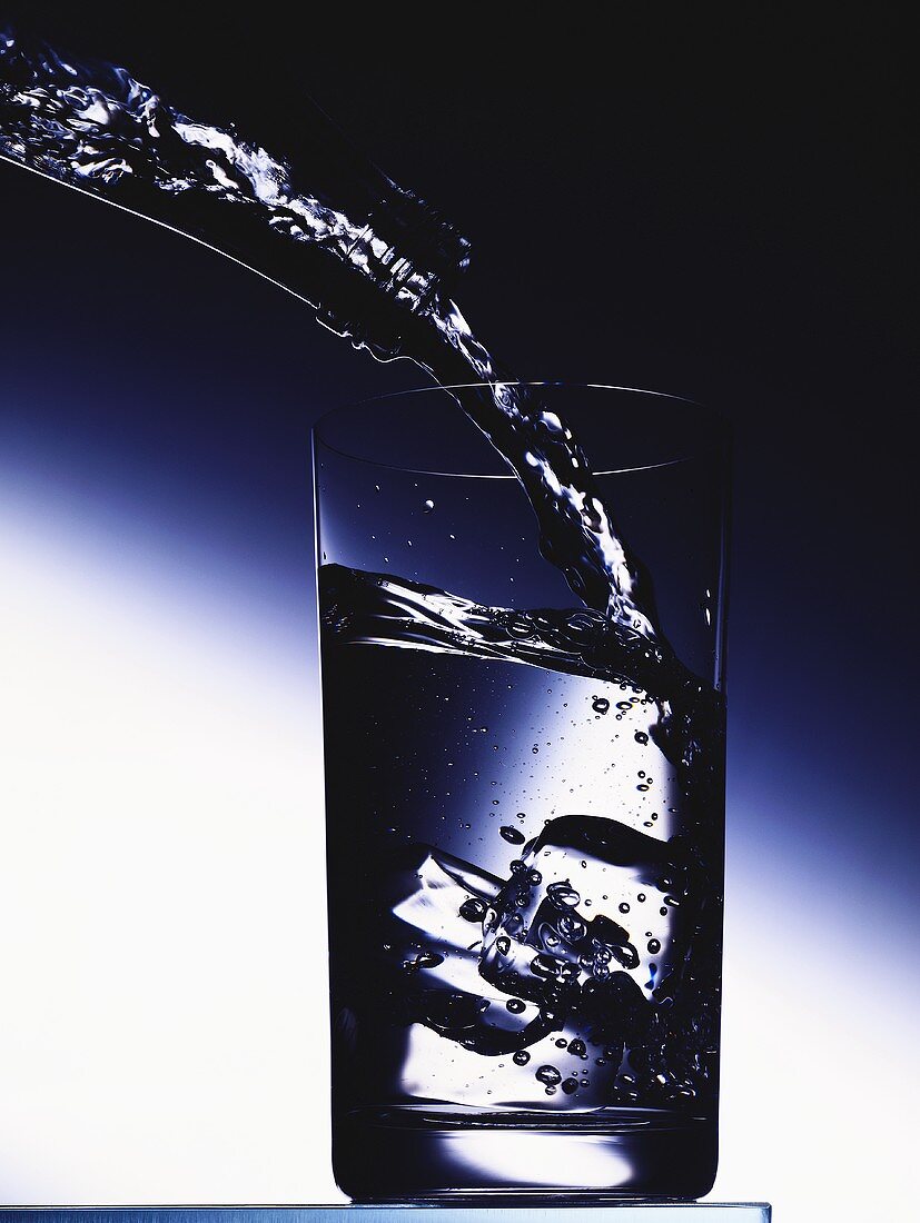 Mineralwasser ins Glas gießen
