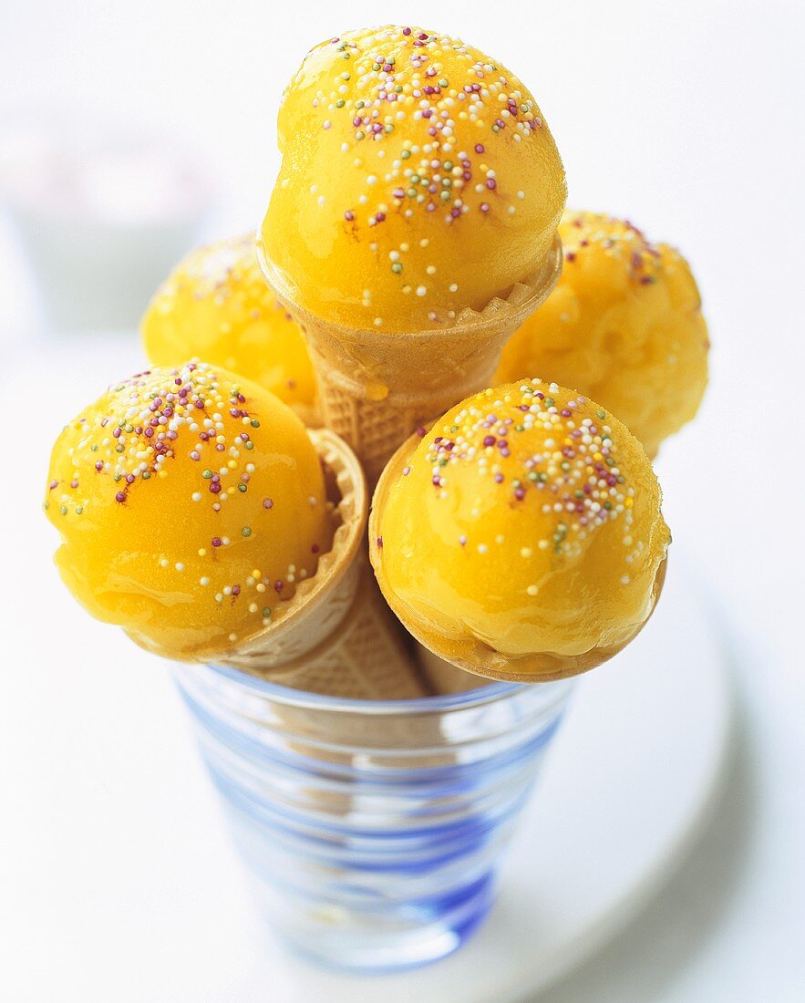 Mango sorbet with sprinkles in ice cream cones