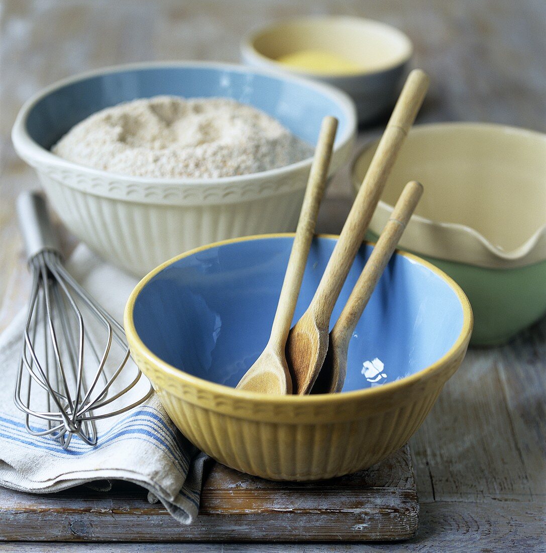 Bowl, wooden spoon, whisk and flour