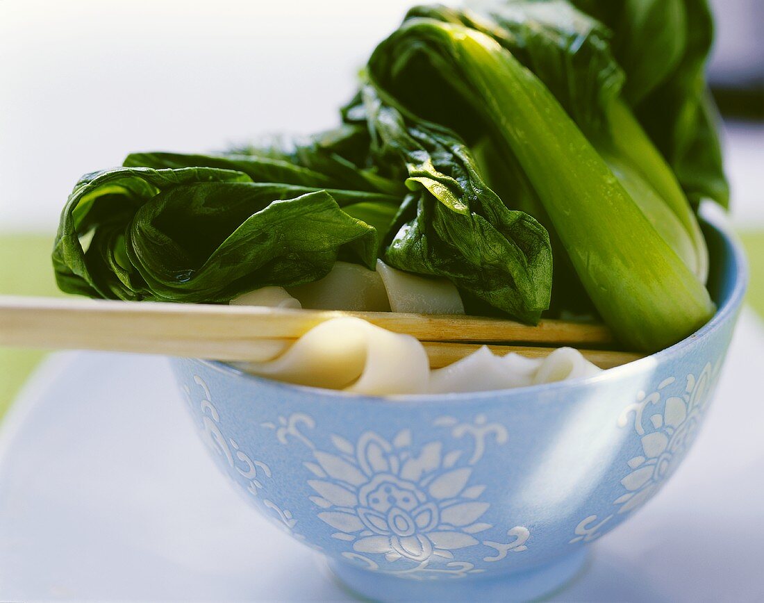 Pak choi with rice noodles in small bowl
