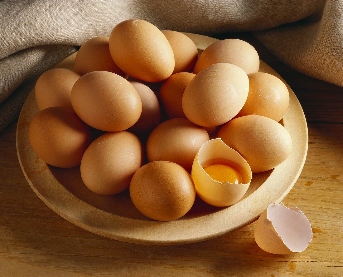 Brown eggs on plate, one egg broken open