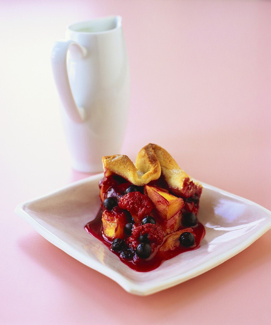 Ein Stück saftiger Beerenkuchen auf einem quadratischen Teller