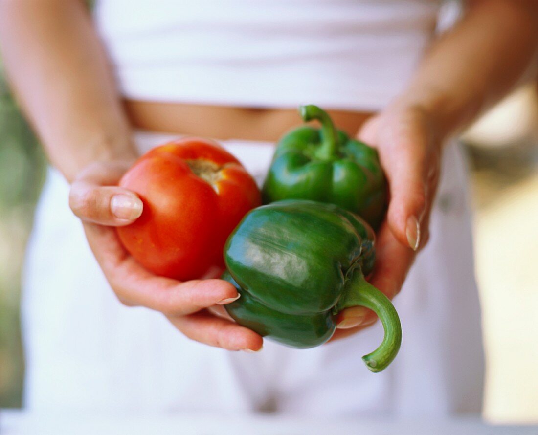 Hands holding peppers and tomato