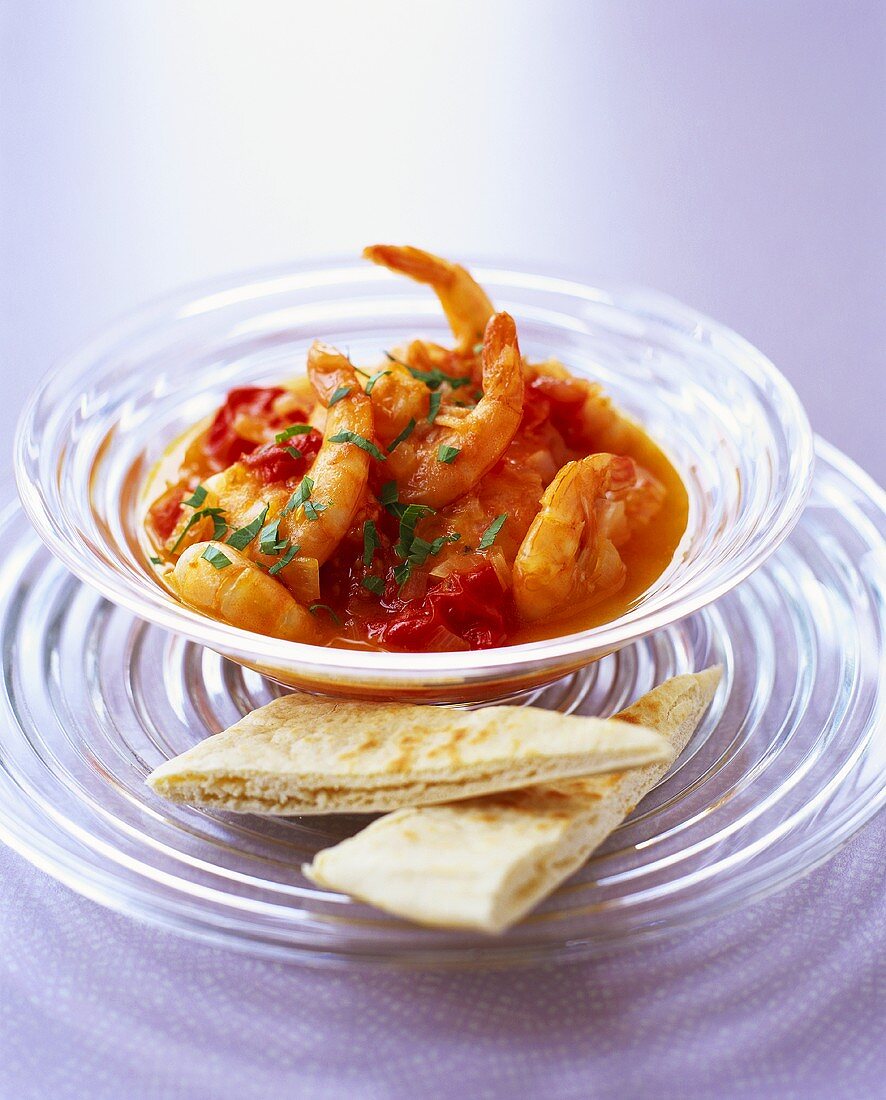 Shrimps in tomato sauce in a glass bowl with pita bread