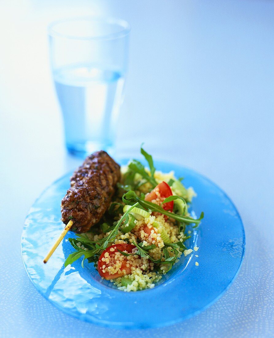 Minced lamb on skewer on couscous salad