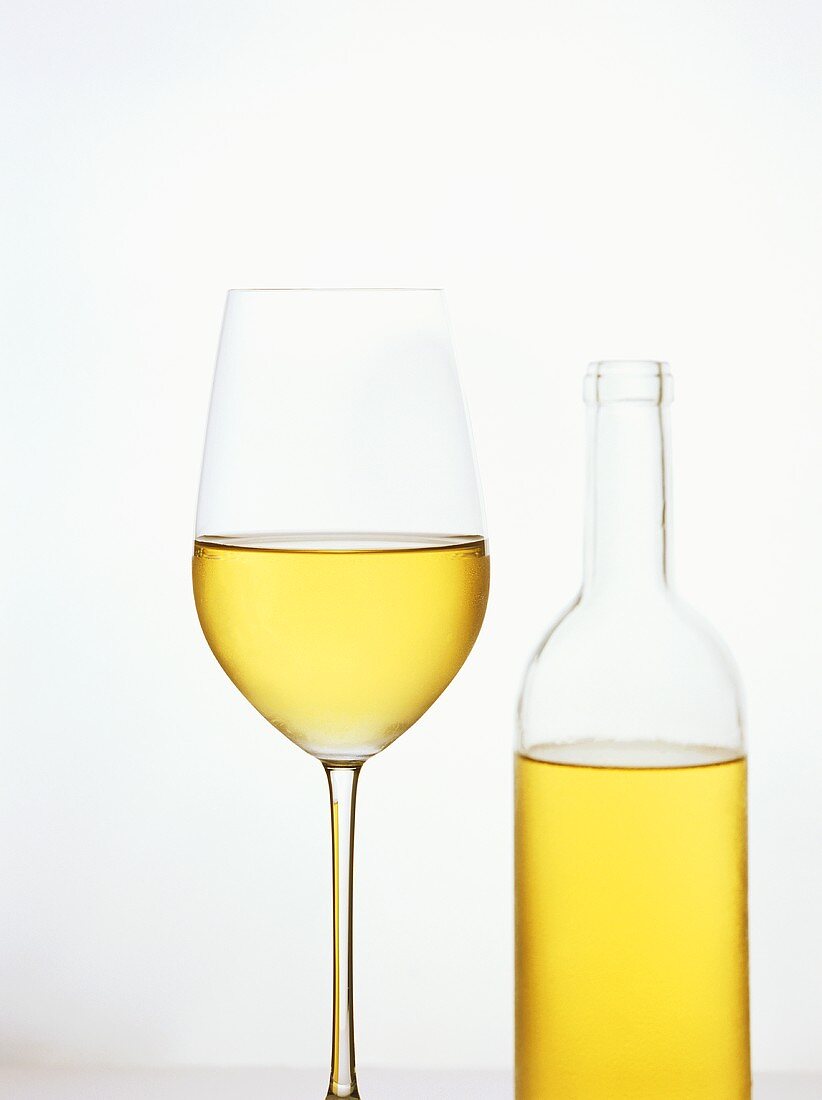 A glass of white wine and a white wine bottle
