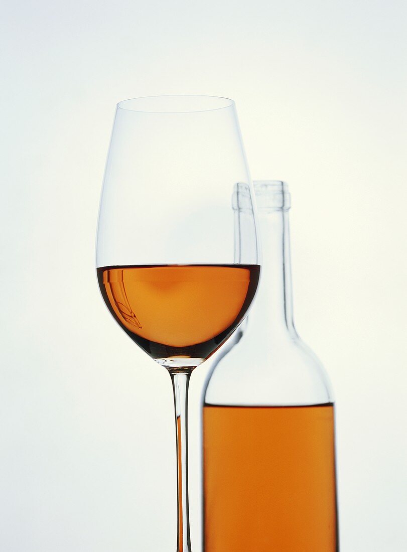 A glass of rosé with a rosé bottle