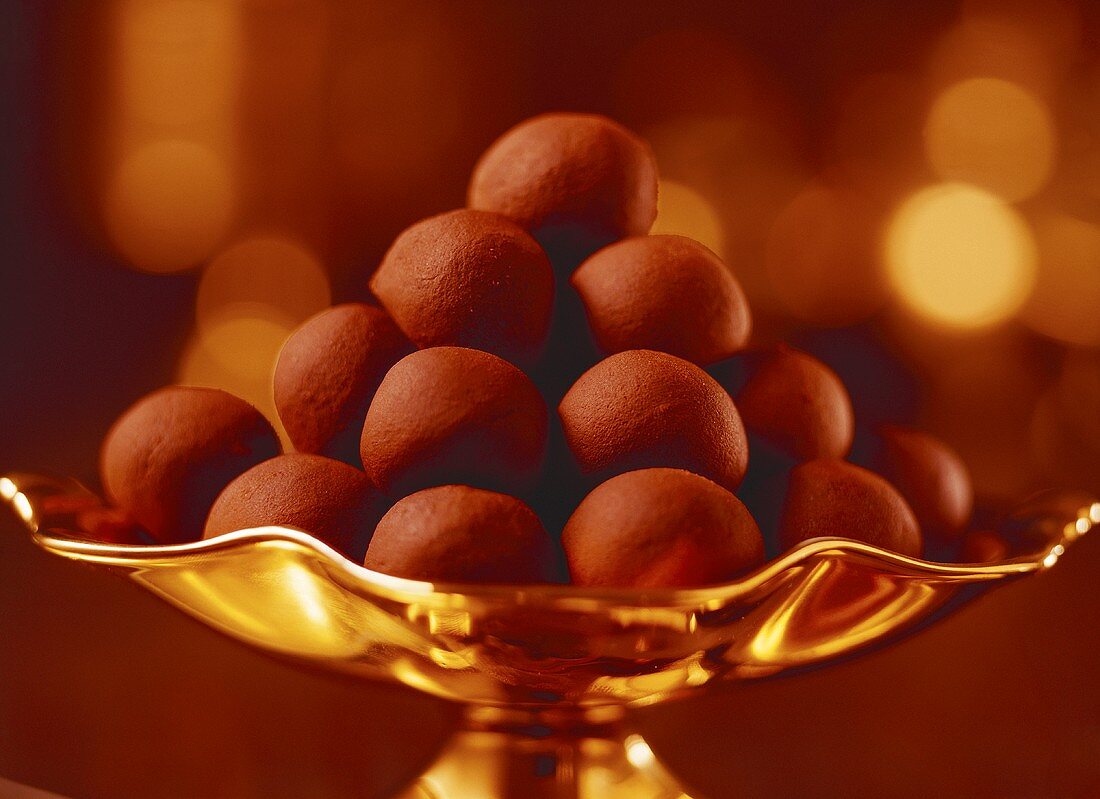A pyramid of chocolate truffles in a golden bowl