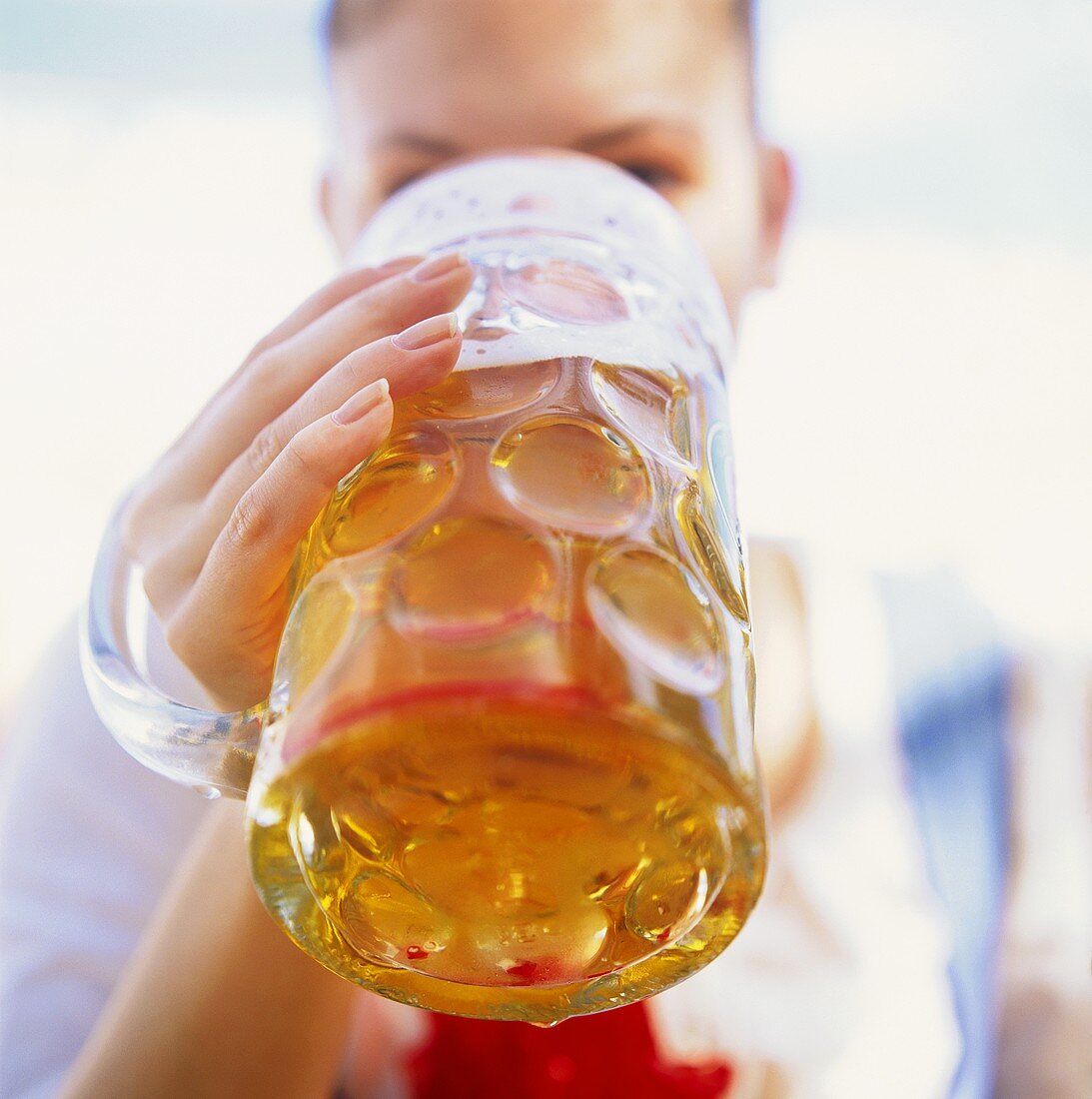 Junge Frau trinkt eine Mass Bier am Oktoberfest (München)