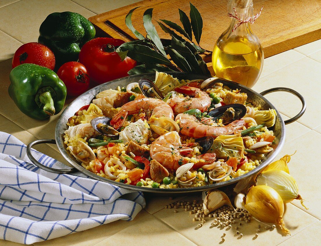 Paella with king prawns in pan, surrounded by ingredients