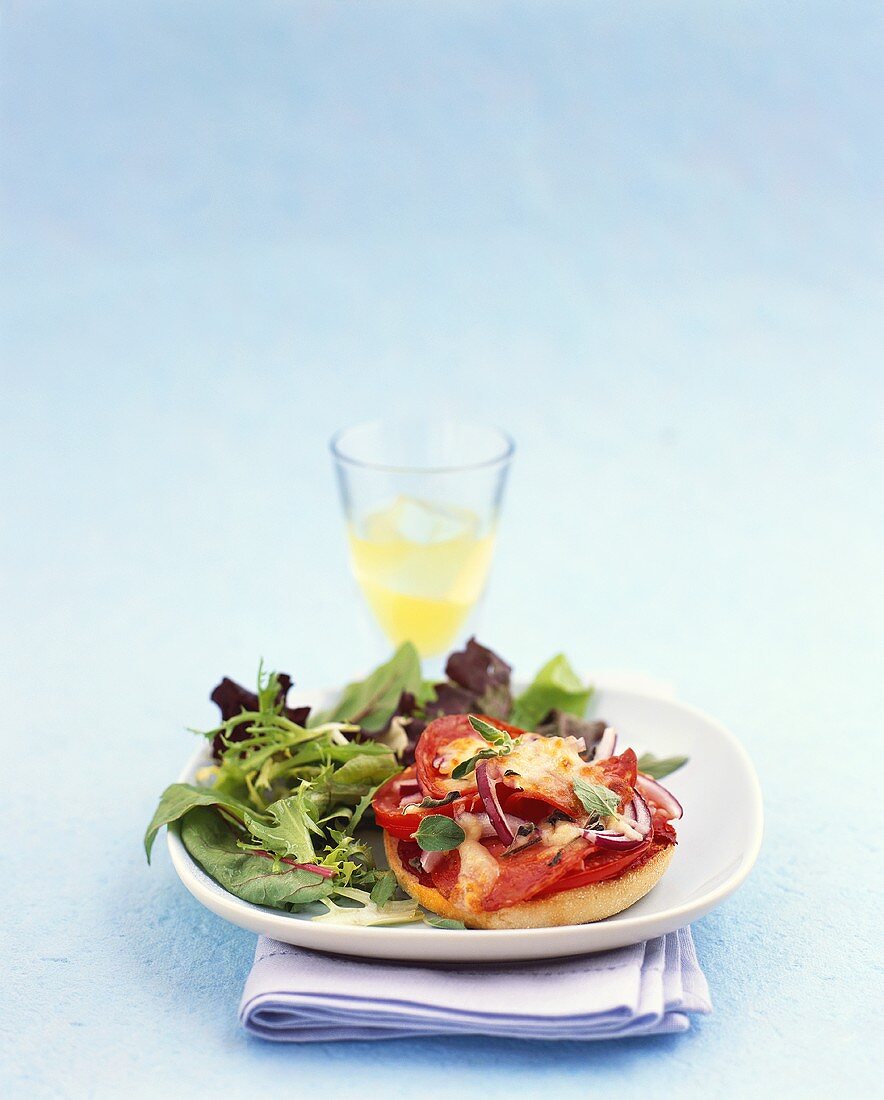 Überbackenes Brötchen mit Wurst, Gemüse und Käse; Salat