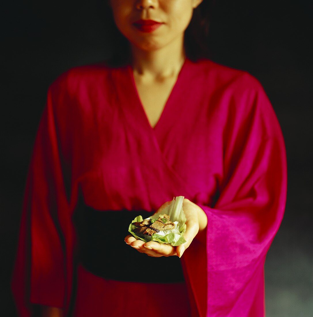 Woman in Japanese kimono presenting Korean dish