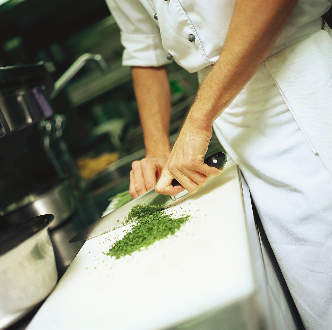 Chef chopping herbs in a kitchen