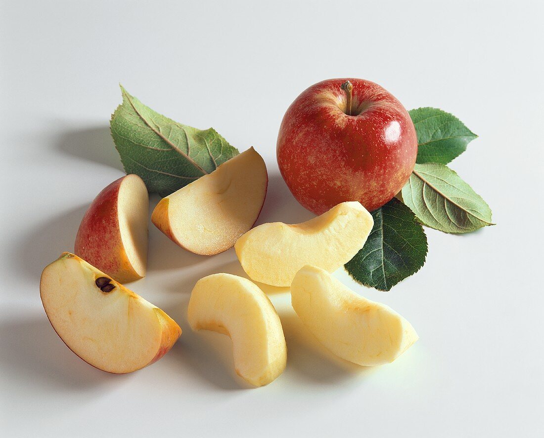 Whole red apple, apple wedges and leaves