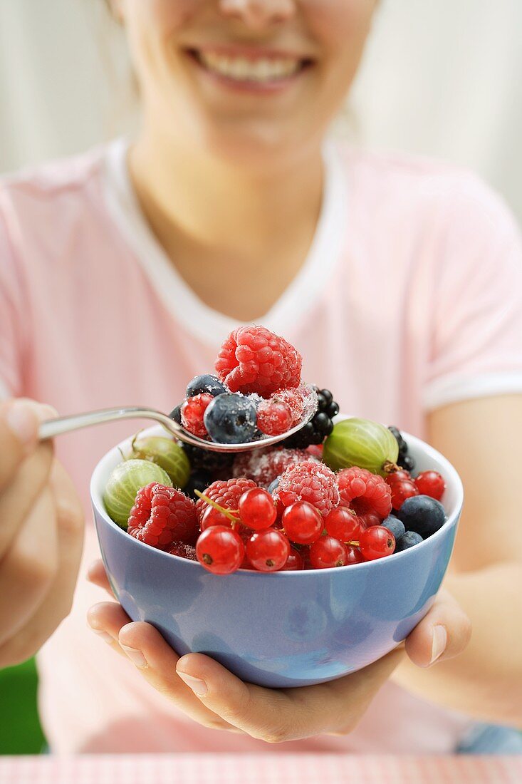 Frau hält Schale mit gezuckerten frischen Beeren