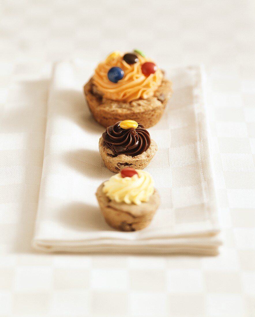 Three muffins with different creams and chocolate beans