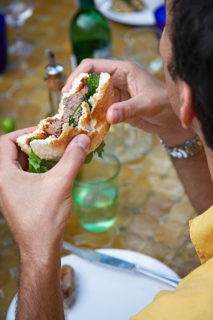 Mann isst Sandwich mit gegrilltem Fleisch
