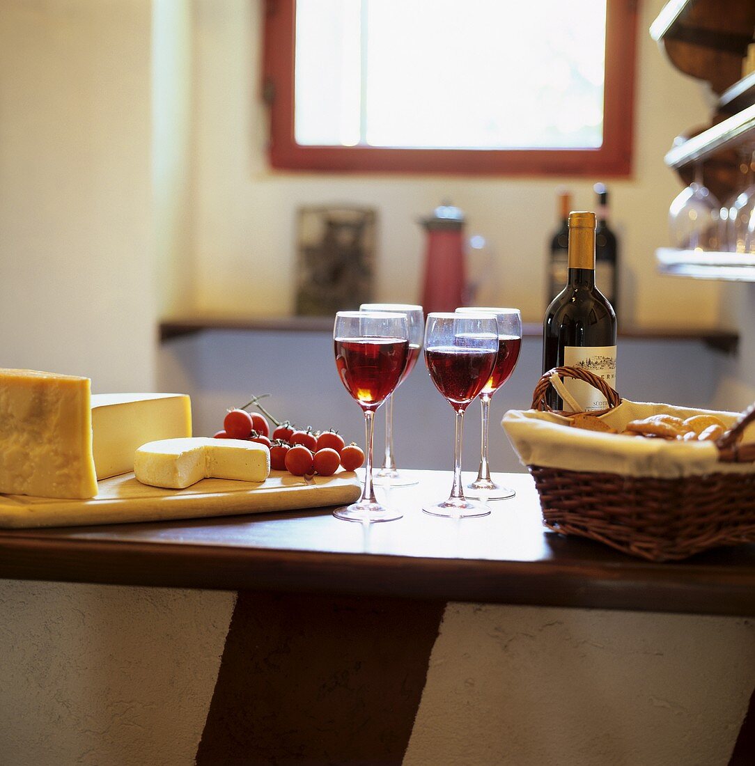 Käseplatte mit Brotkörbchen und Rotwein