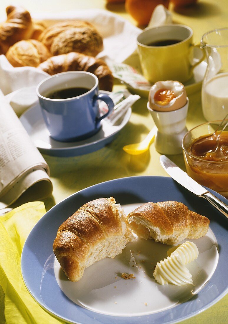 Frühstück mit Croissant, Marmelade, Ei und Kaffee
