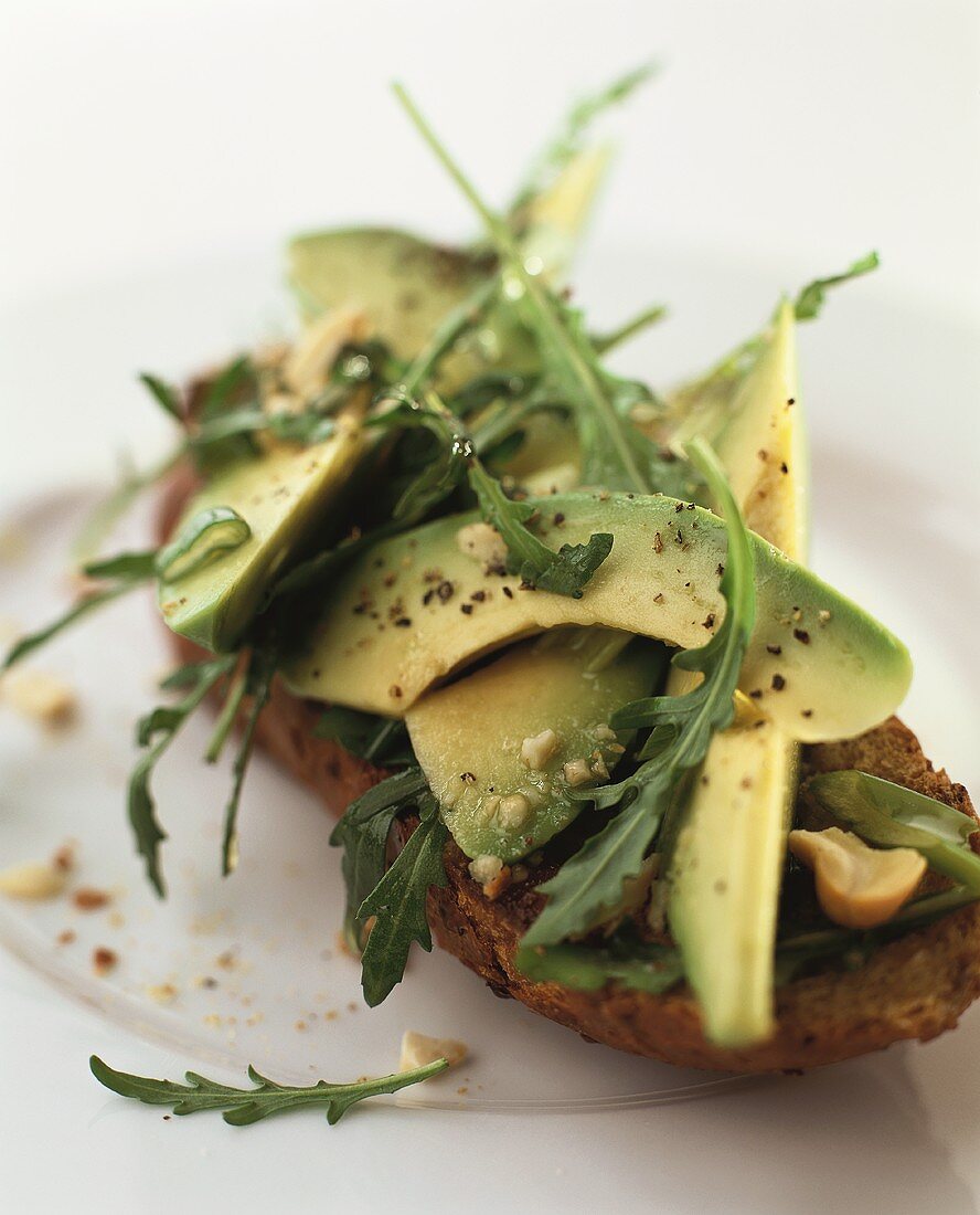 Slice of bread topped with avocado and rocket