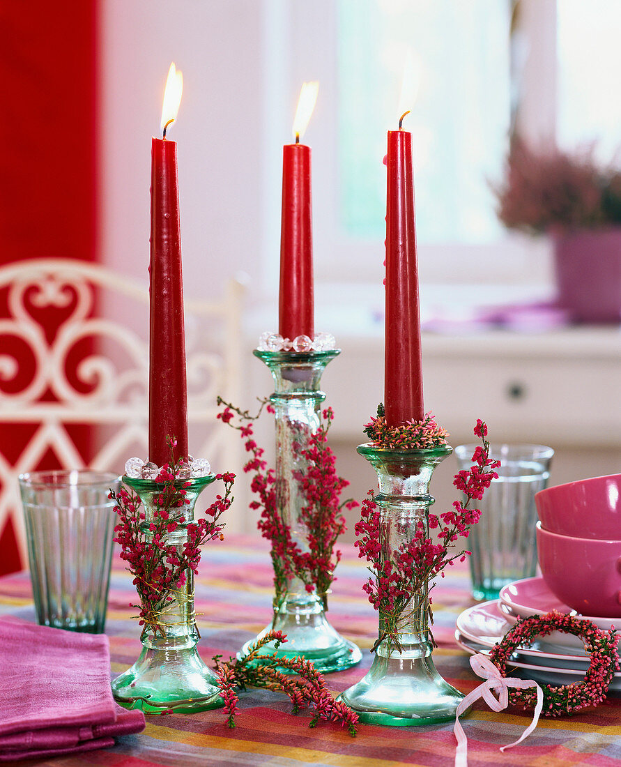 Glass candlestick with red candles, coffee things behind