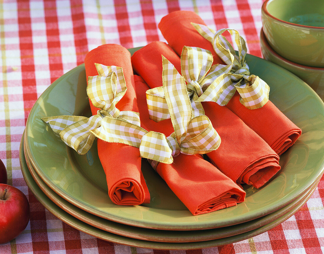 Red napkins with checked bows on green plates