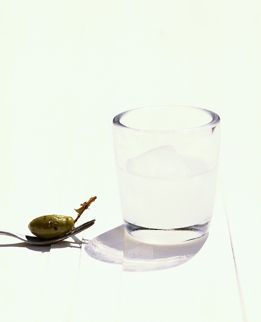 A glass of ouzo and a green olive