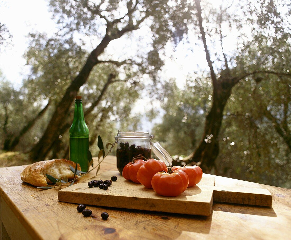 Stillleben mit Weißbrot, schwarzen Oliven und Tomaten