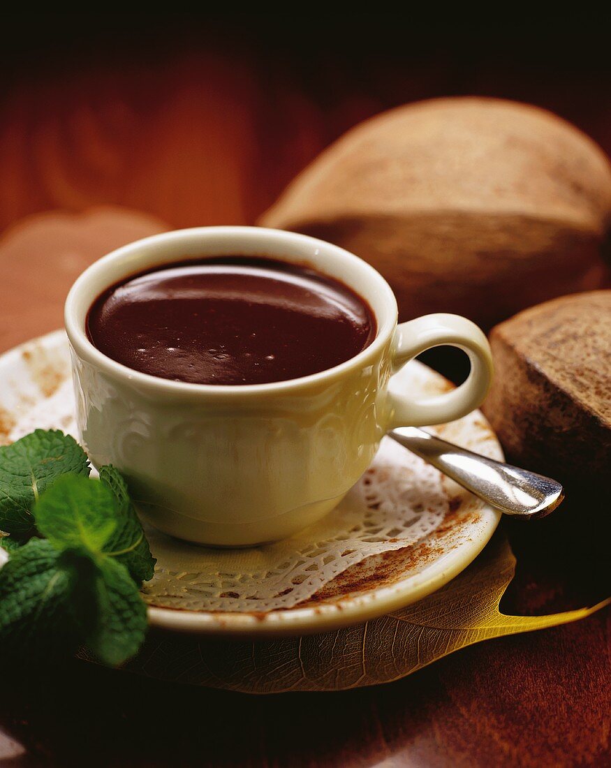 A cup of chocolate, cocoa beans in background