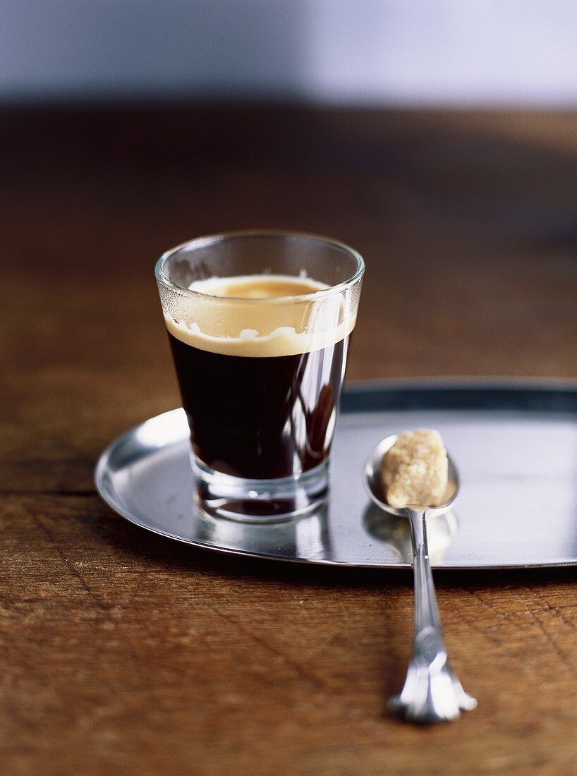 Espresso im Glas und brauner Würfelzucker