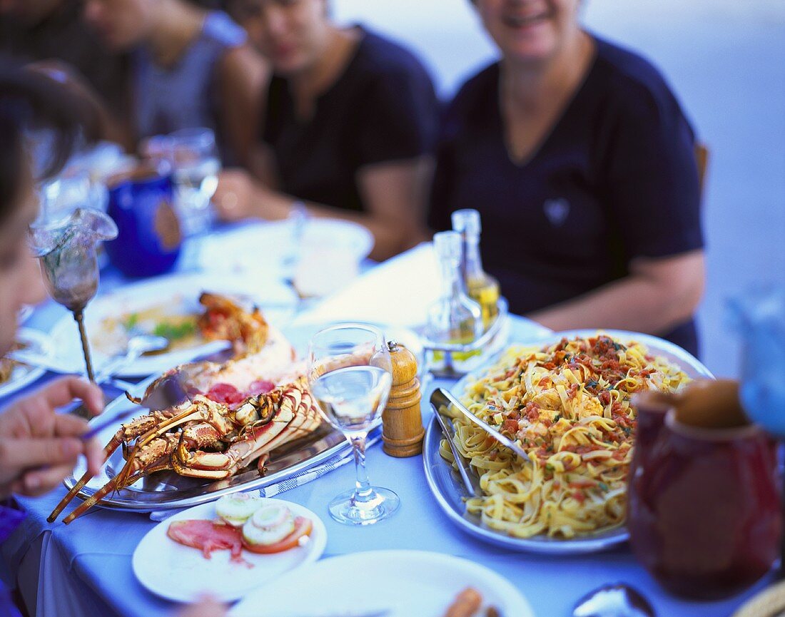 Menschen am Tisch mit Meeresfrüchte- & Fischgerichten