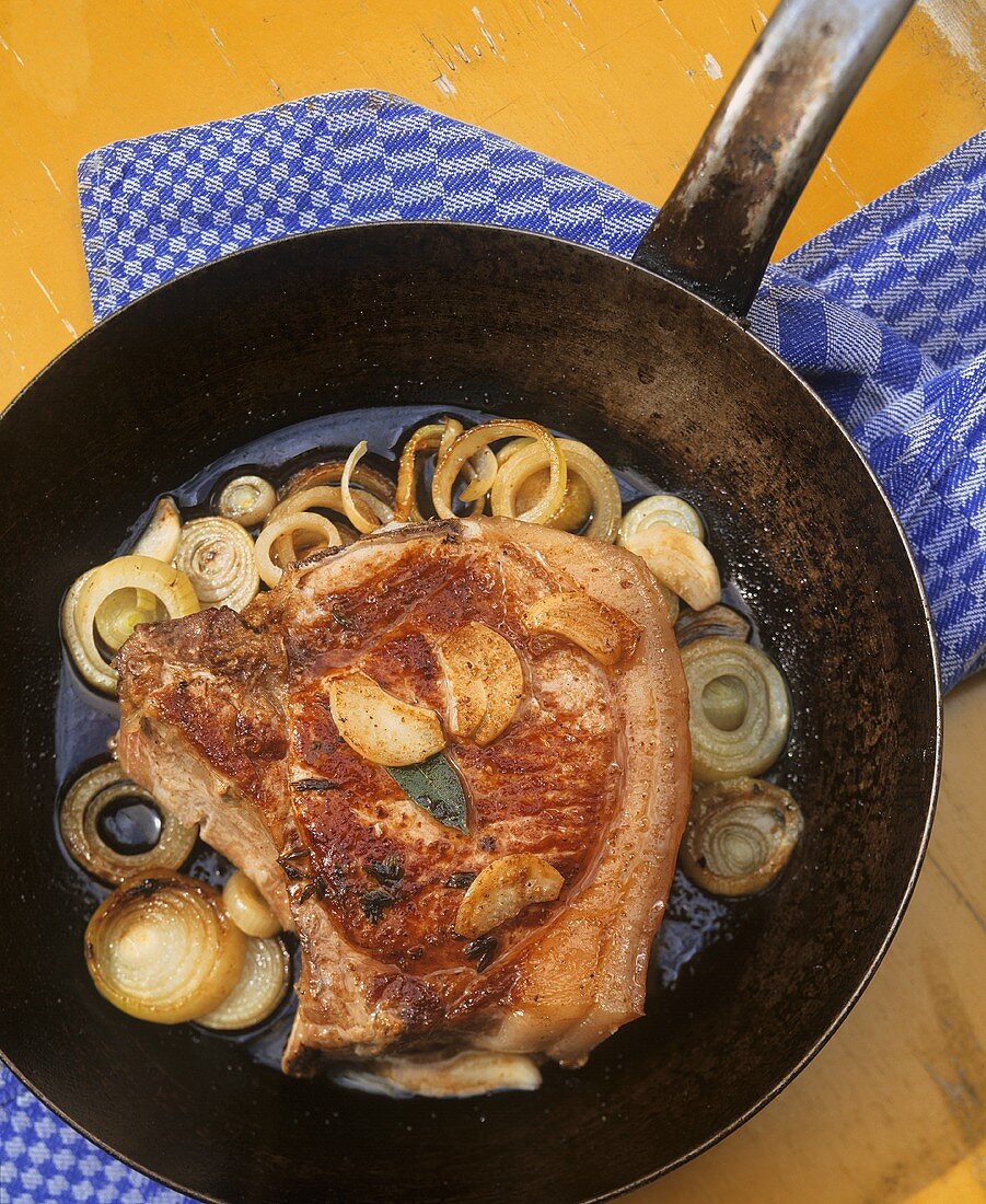 Pork chop with onion rings in a frying pan