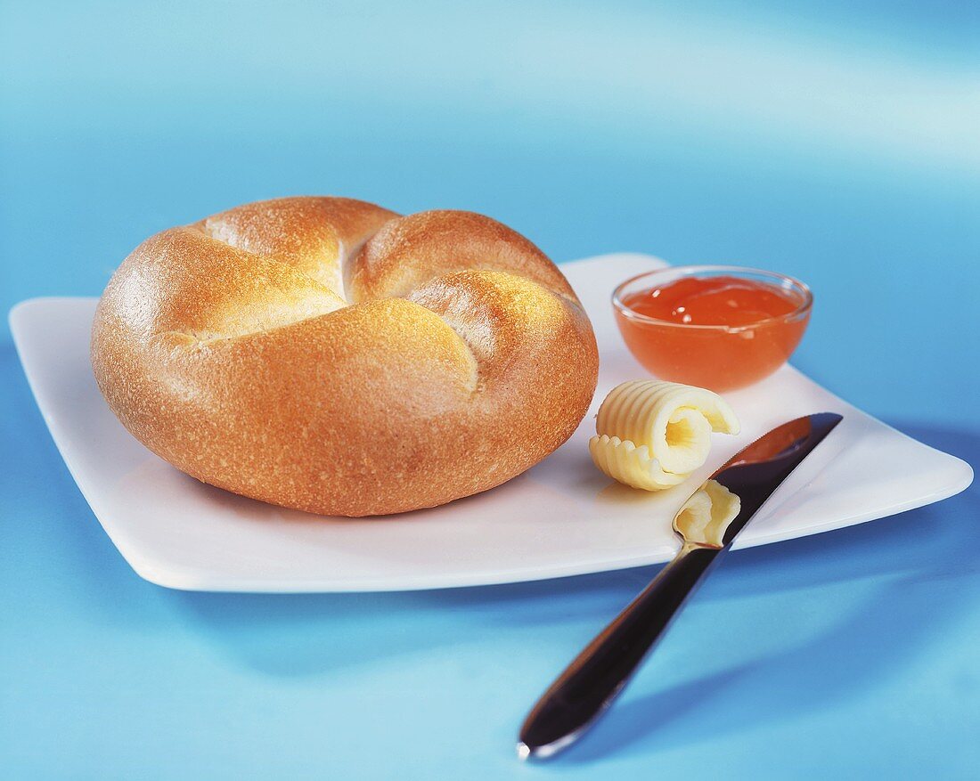 Bread roll with butter curl and jam