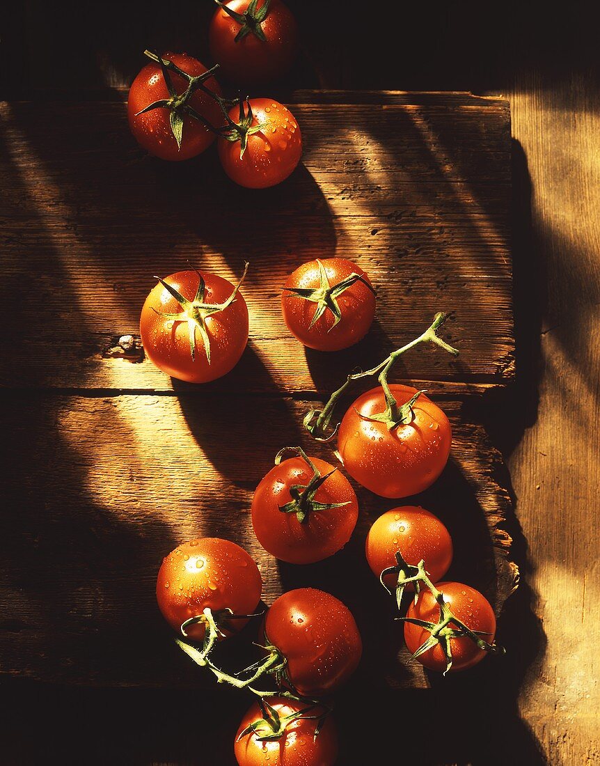Tomatoes with drops of water on wooden background