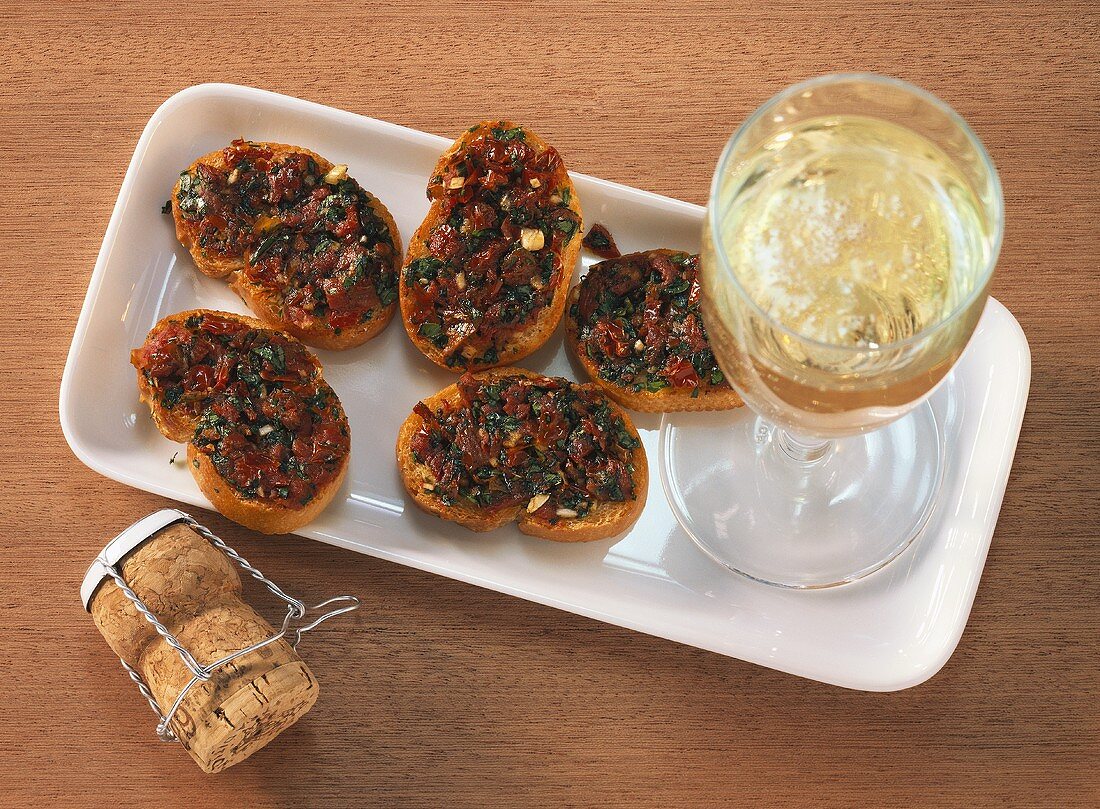Crostini with dried tomatoes and a glass of white wine