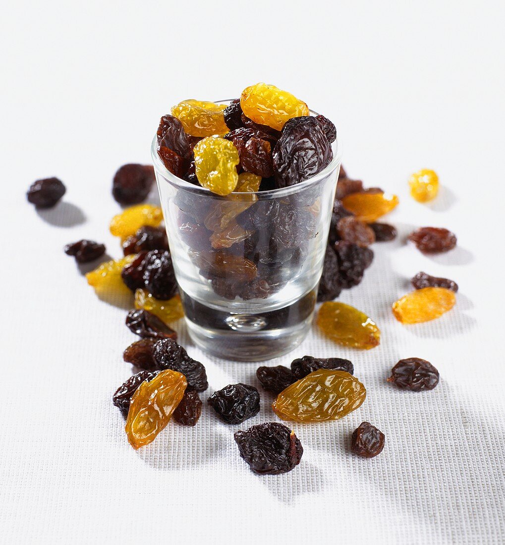 Raisins and sultanas in and beside a small glass