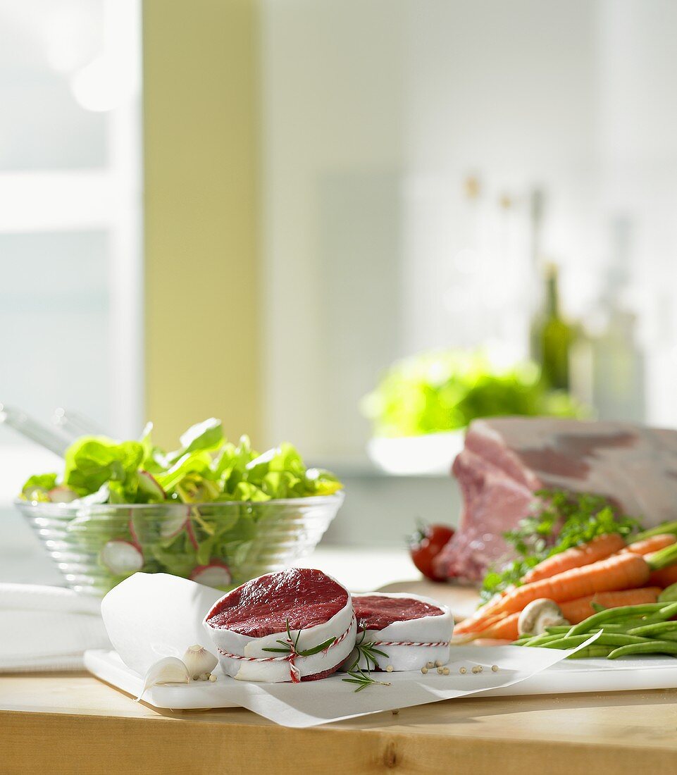 Küchenszene mit Fleisch, Salat und Gemüse bei Zubereitung