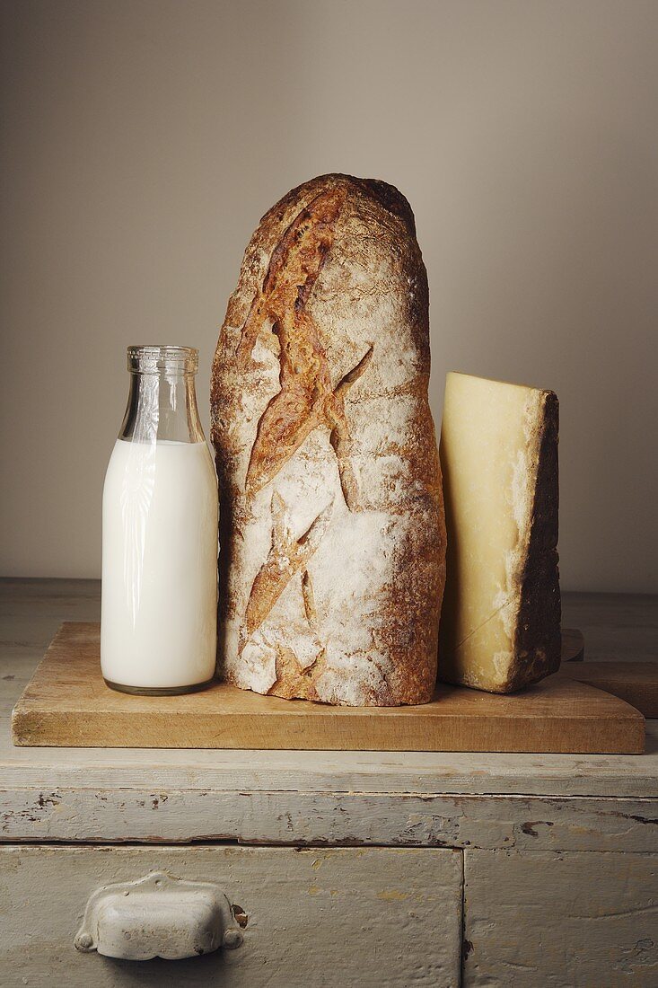 Milk bottle, bread and cheese on a wooden cupboard