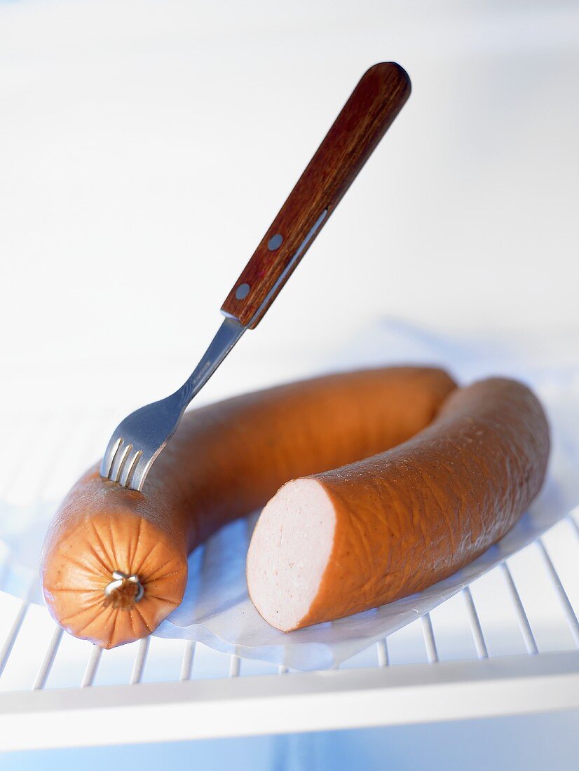 Fleischwurst mit einer Gabel im Kühlschrank