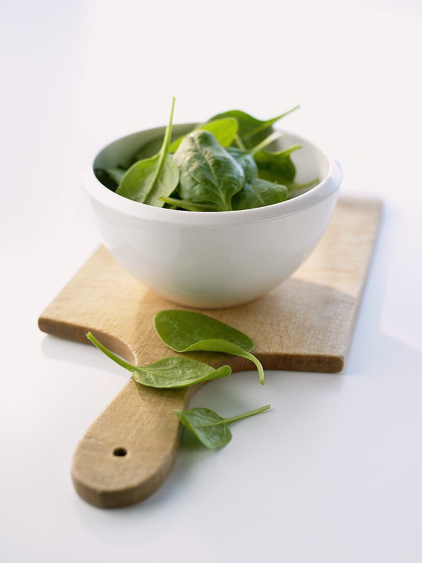 Spinach in a bowl and on a wooden board
